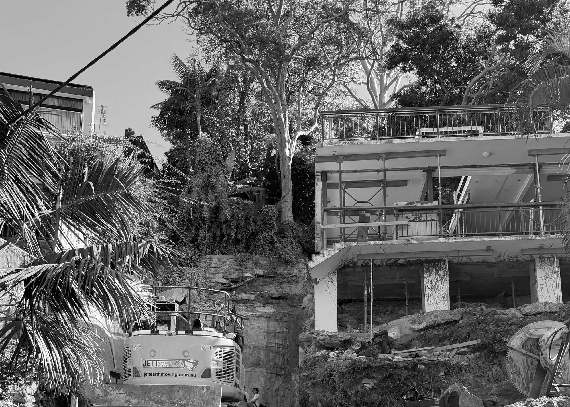 Excavation beneath the existing house at Kiora, an excavator among the palms