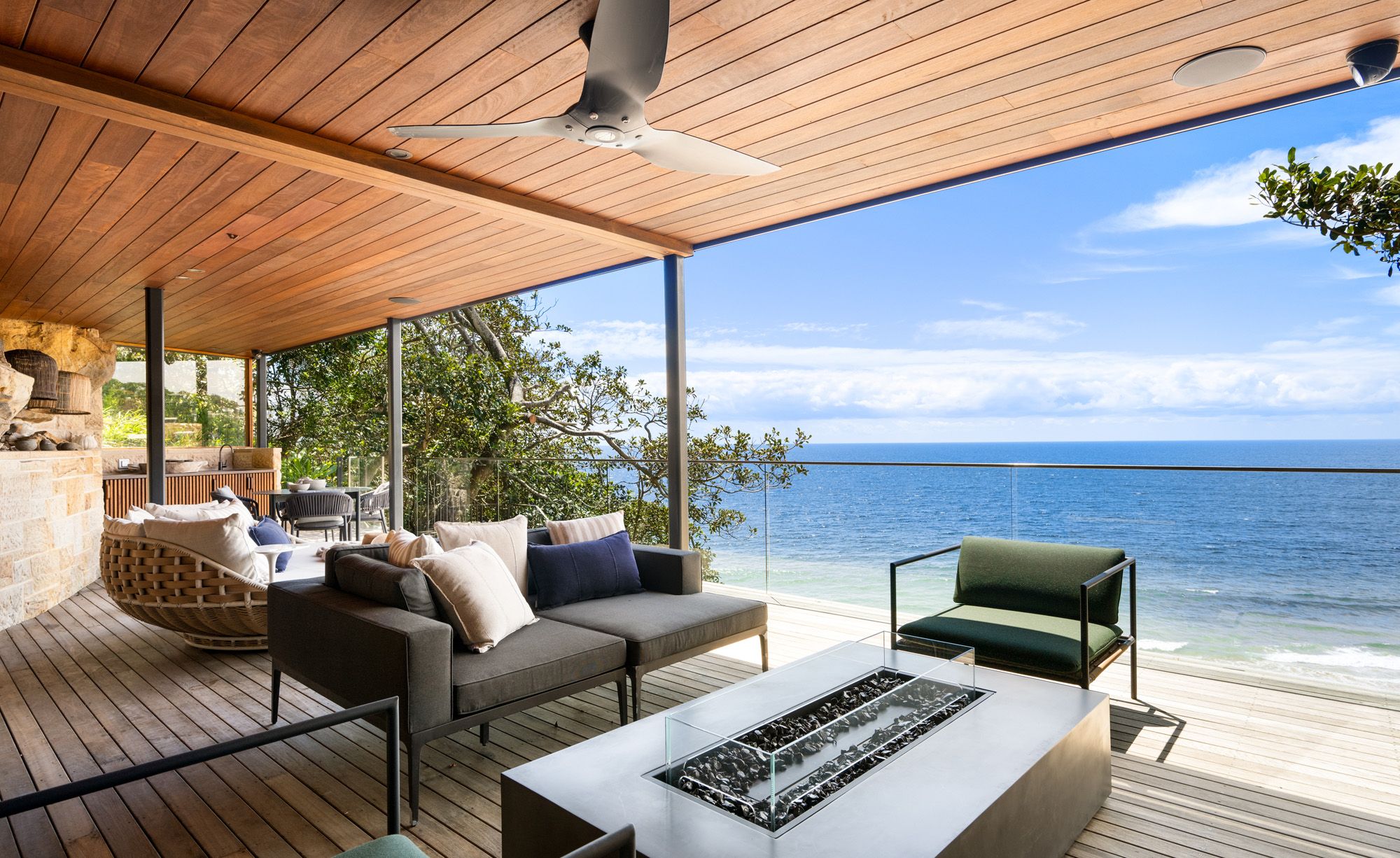 Covered deck with lounges and a fire table facing the ocean