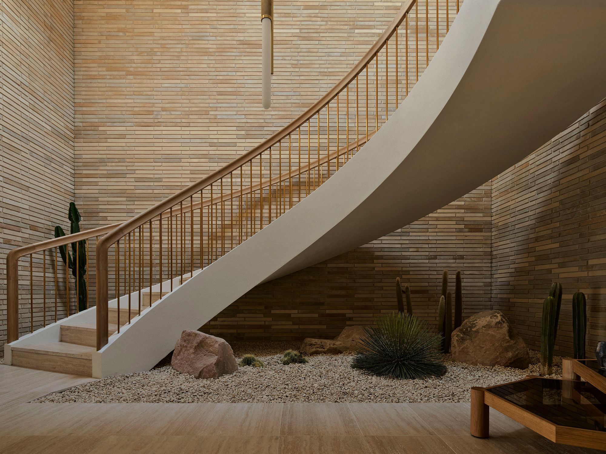 Curved staircase sweeping over a gravel garden inside Breeze House
