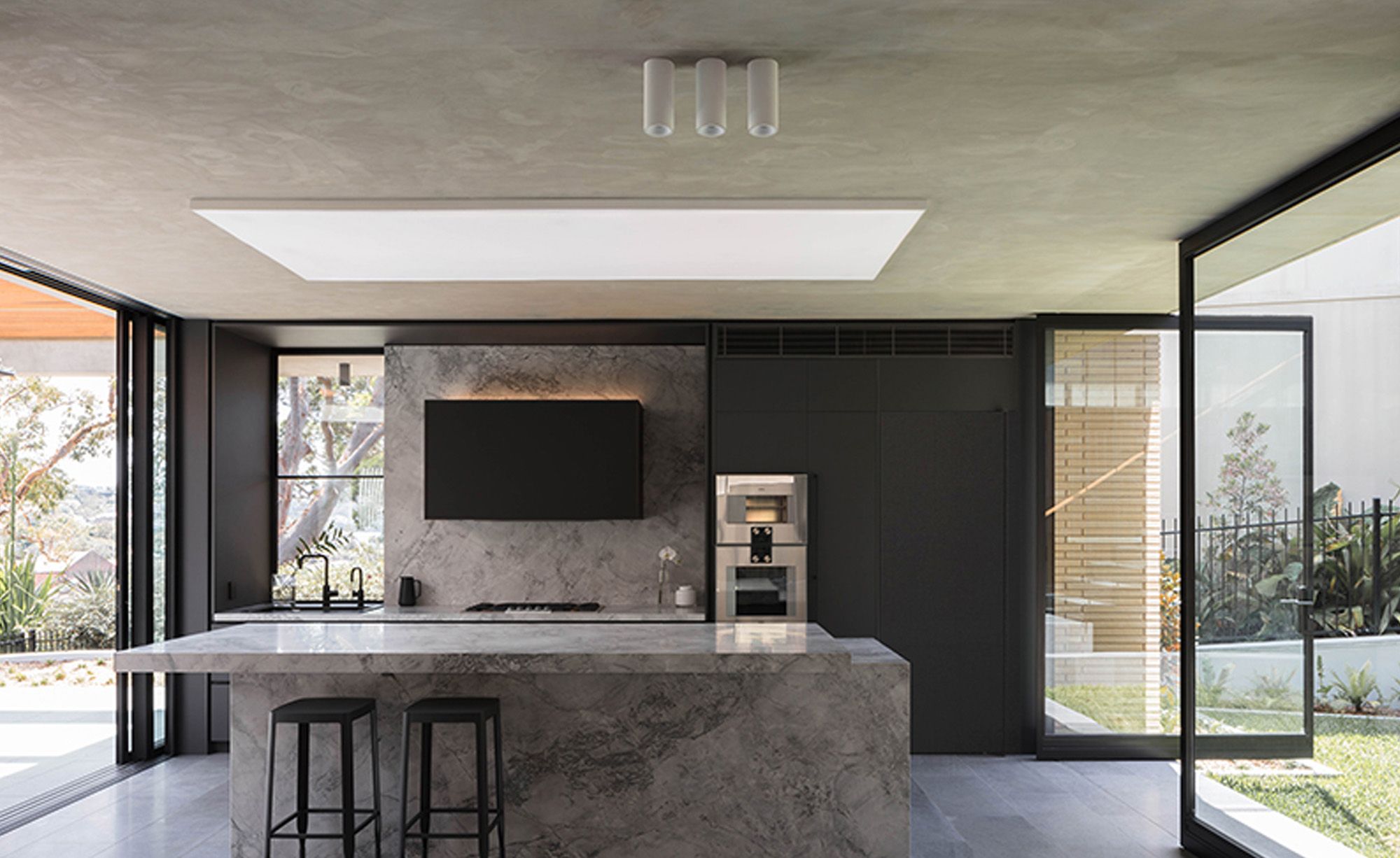 Kitchen with a marble island and a skylight, framed by brick columns
