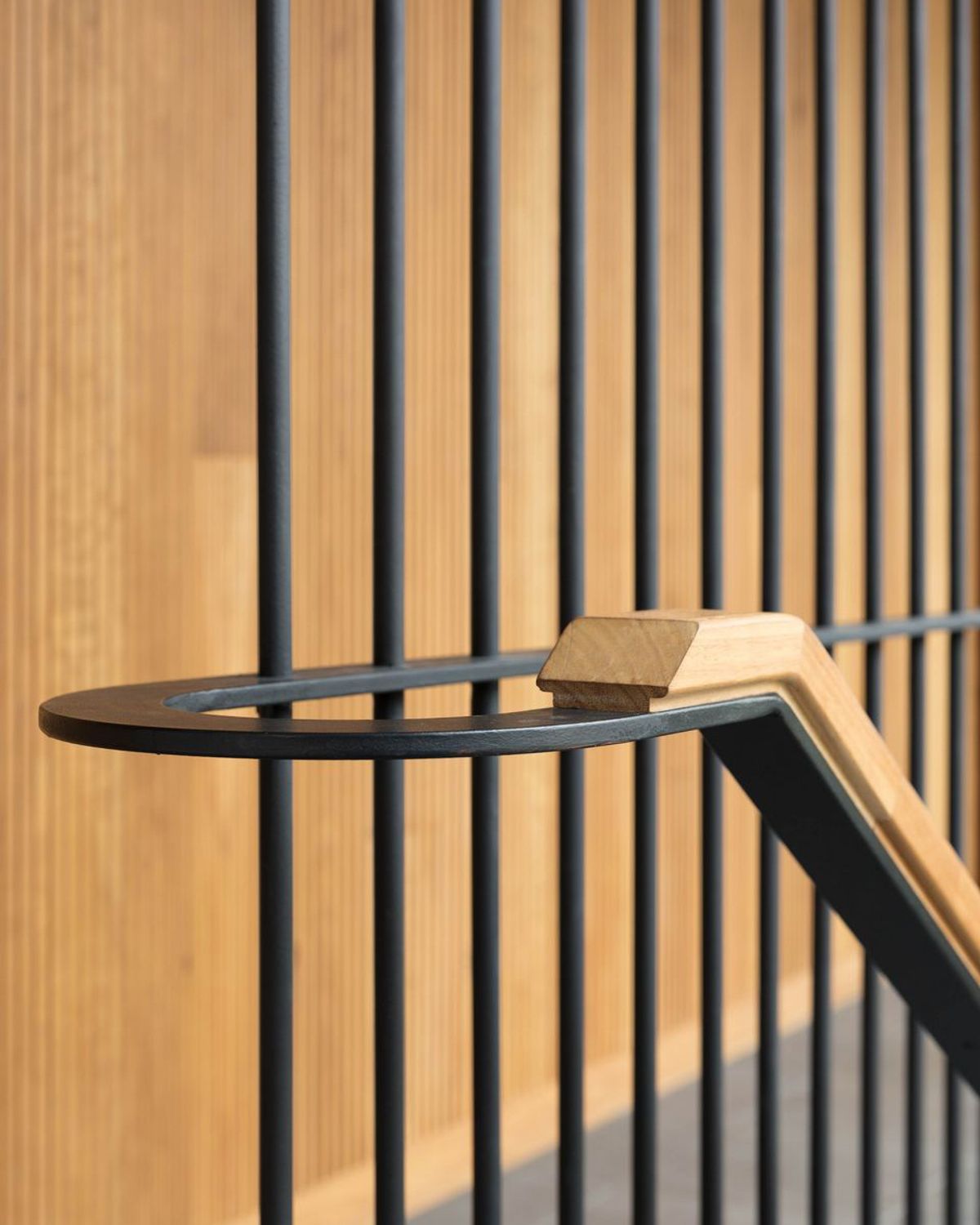 Timber handrail with a steel bracket against a timber battened wall