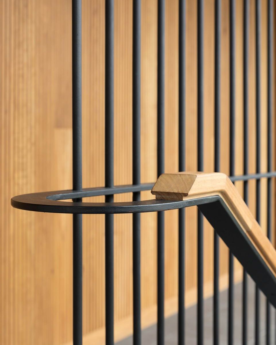 Timber handrail with a steel bracket against a timber battened wall