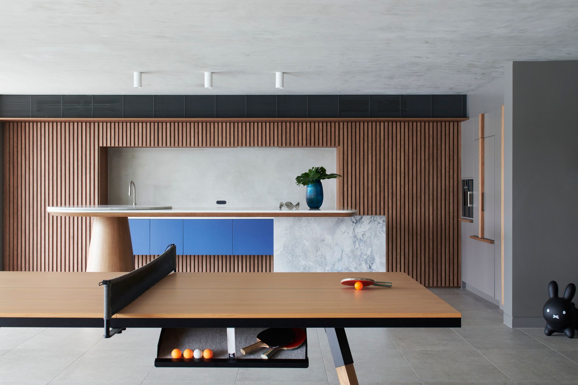 Kitchen with a timber battened wall, table tennis table and blue joinery