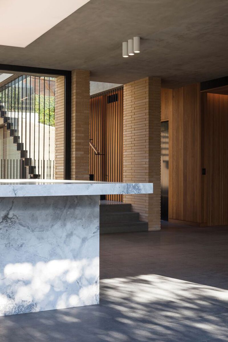 Marble kitchen island with brick and timber walls beyond