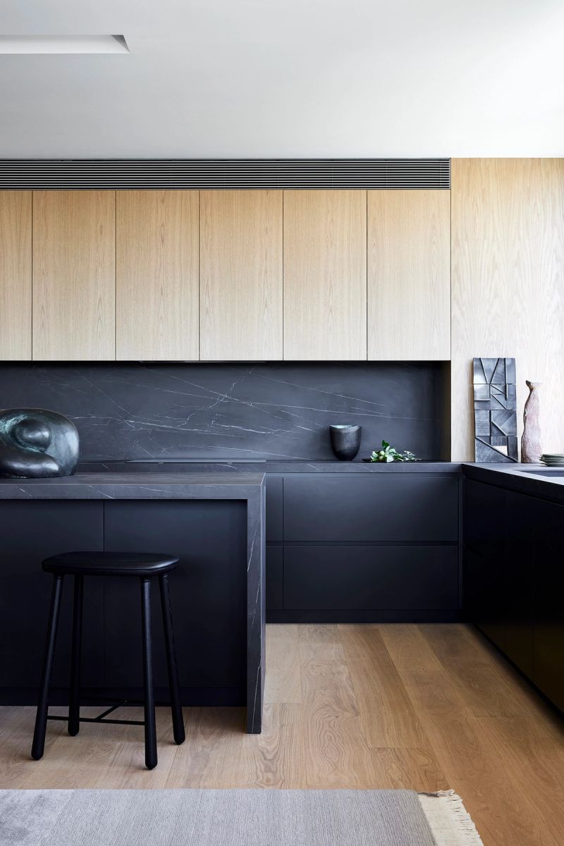 Kitchen with pale timber upper cabinets and a black stone island