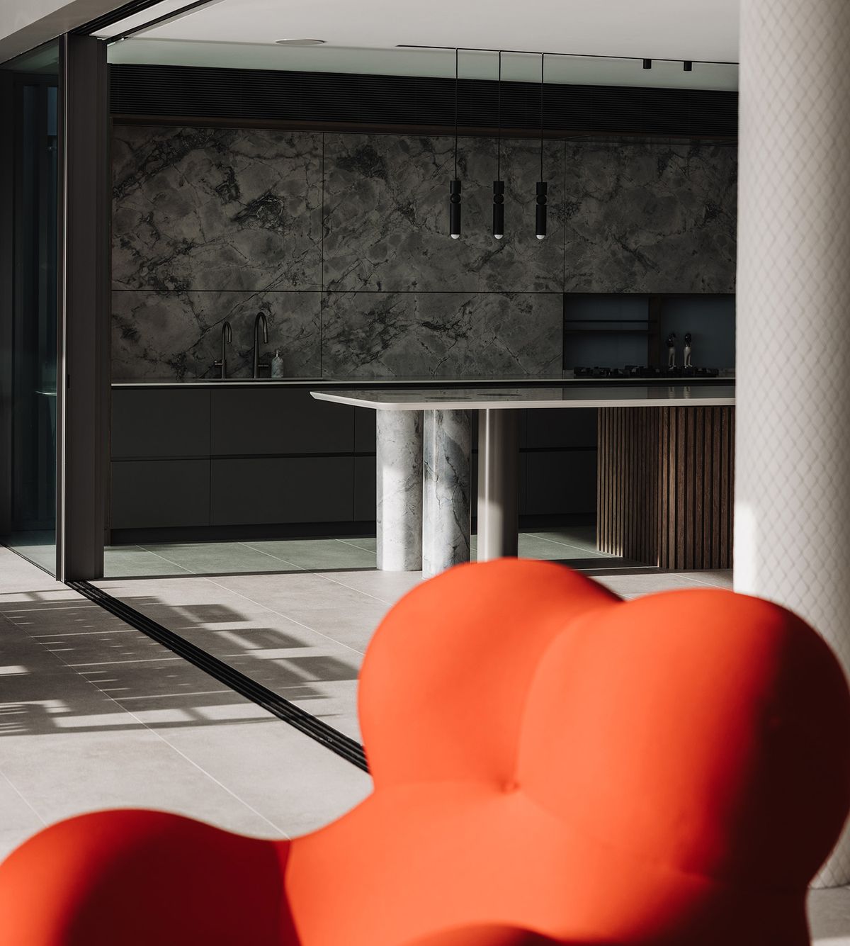 Shellbank kitchen with a marble island on stone columns, an orange armchair in the foreground