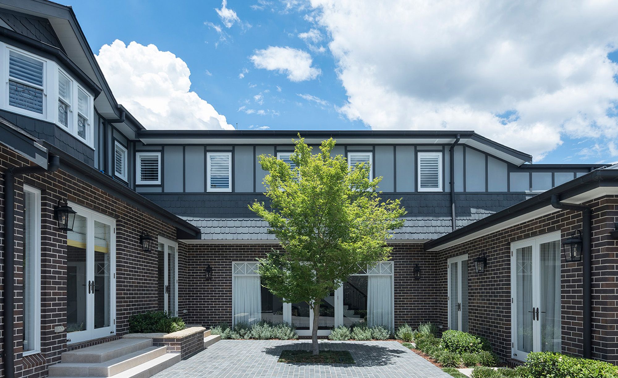 Sussex House courtyard with a tree, brick walls and slate roofs