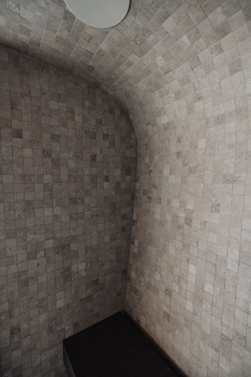 Curved shower wall in small stone tiles