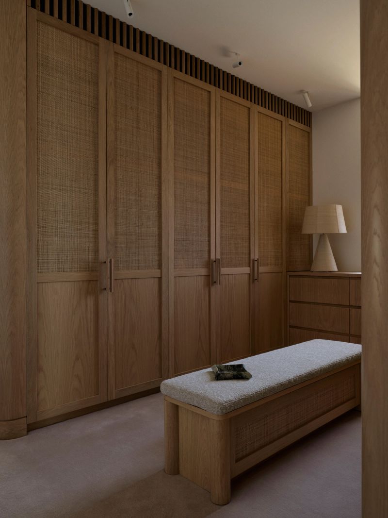 Dressing room with rattan fronted timber wardrobes and an upholstered bench