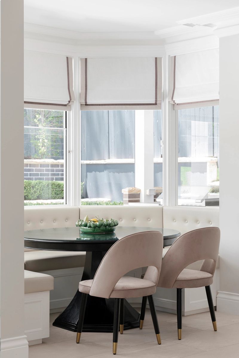 Round breakfast table in a bay window with a banquette seat