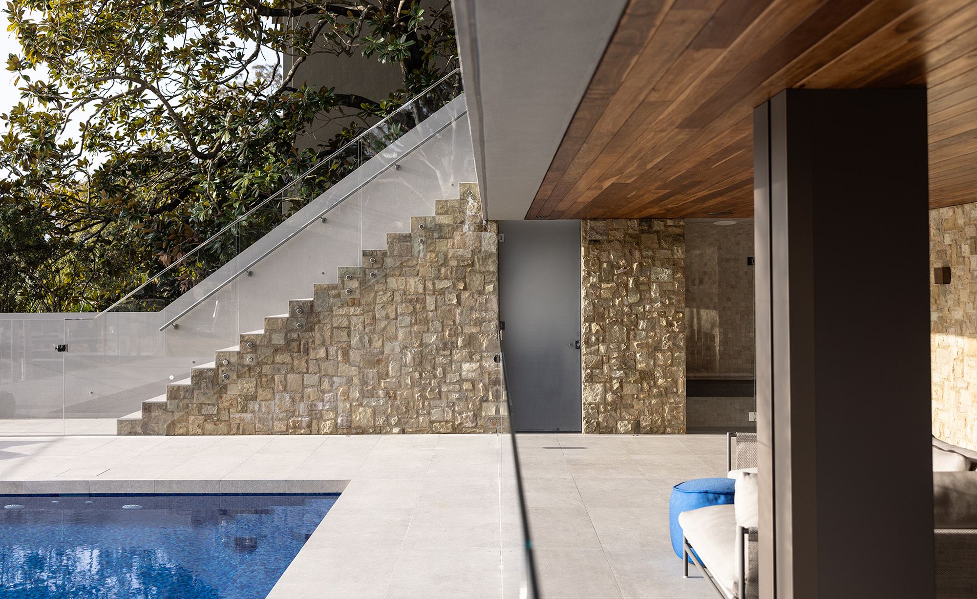 Pool terrace with a sandstone wall and stair beneath the timber lined roof