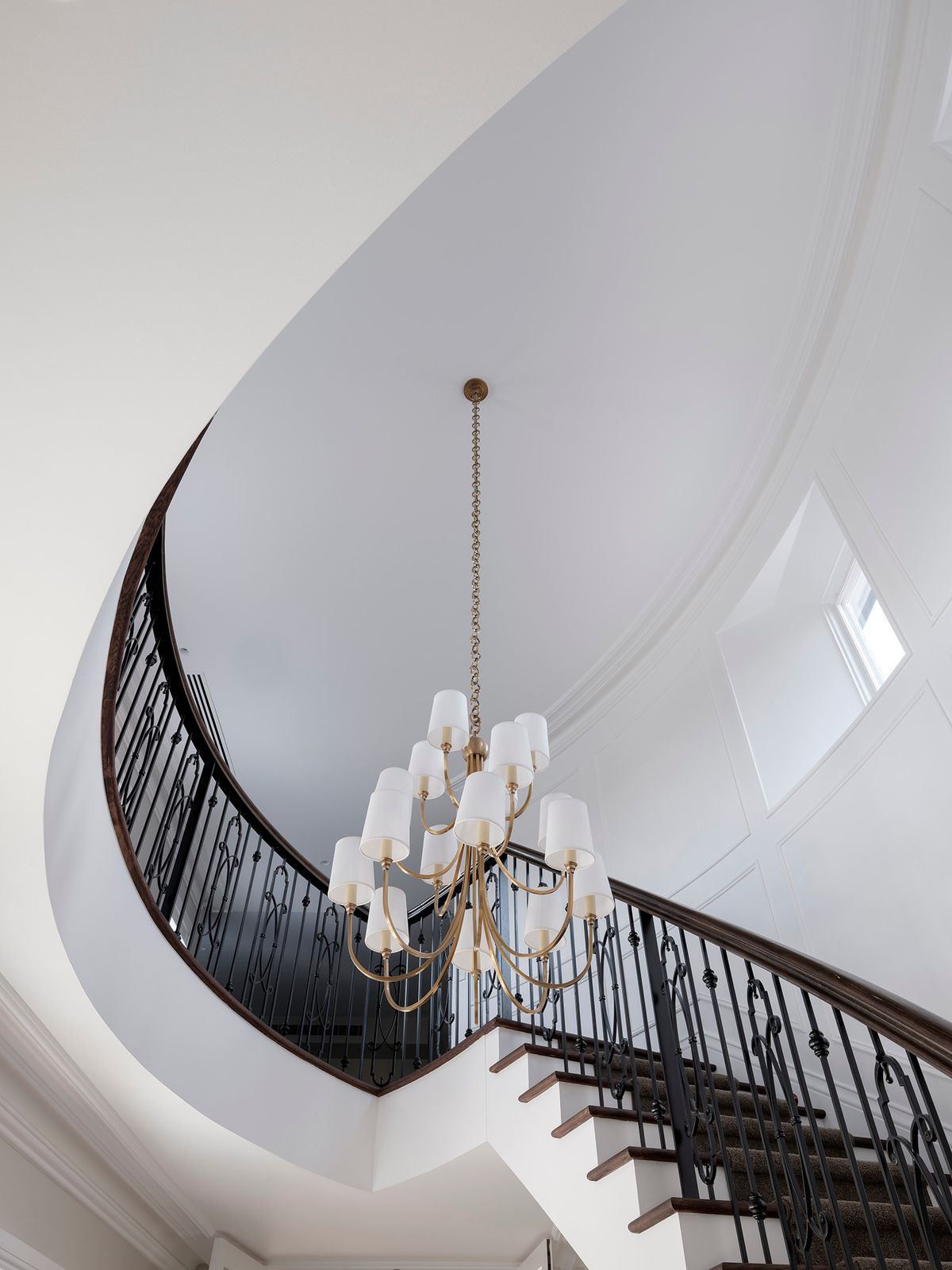 Curved staircase and pendant chandelier seen from below at Sussex House
