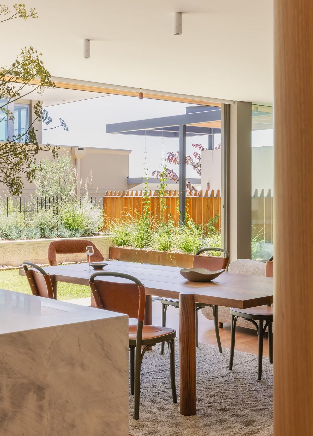 Dining table beside a marble island at Casa Risata, opening to the lawn and garden