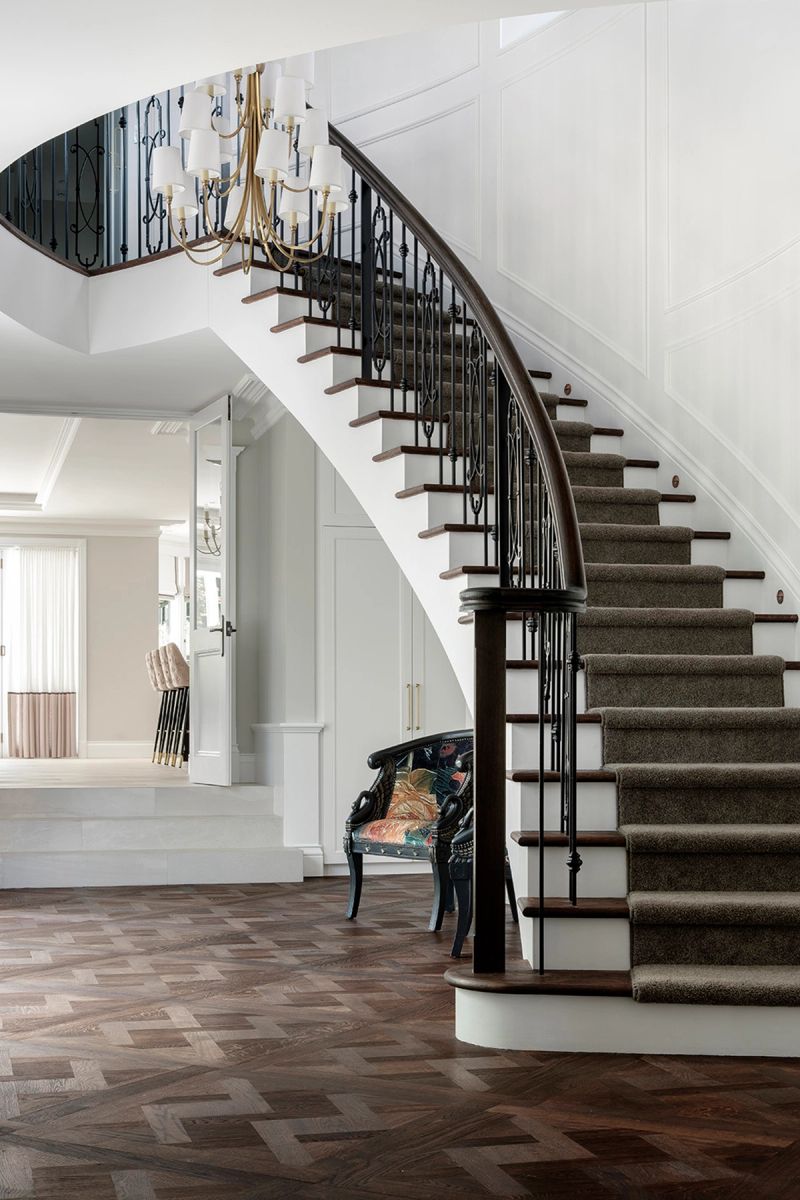 Curved staircase with wrought iron balustrade and a carpet runner