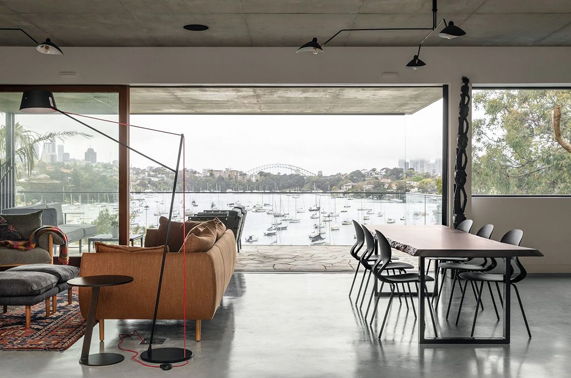 Bay House living and dining room open to the harbour, the city skyline in the distance