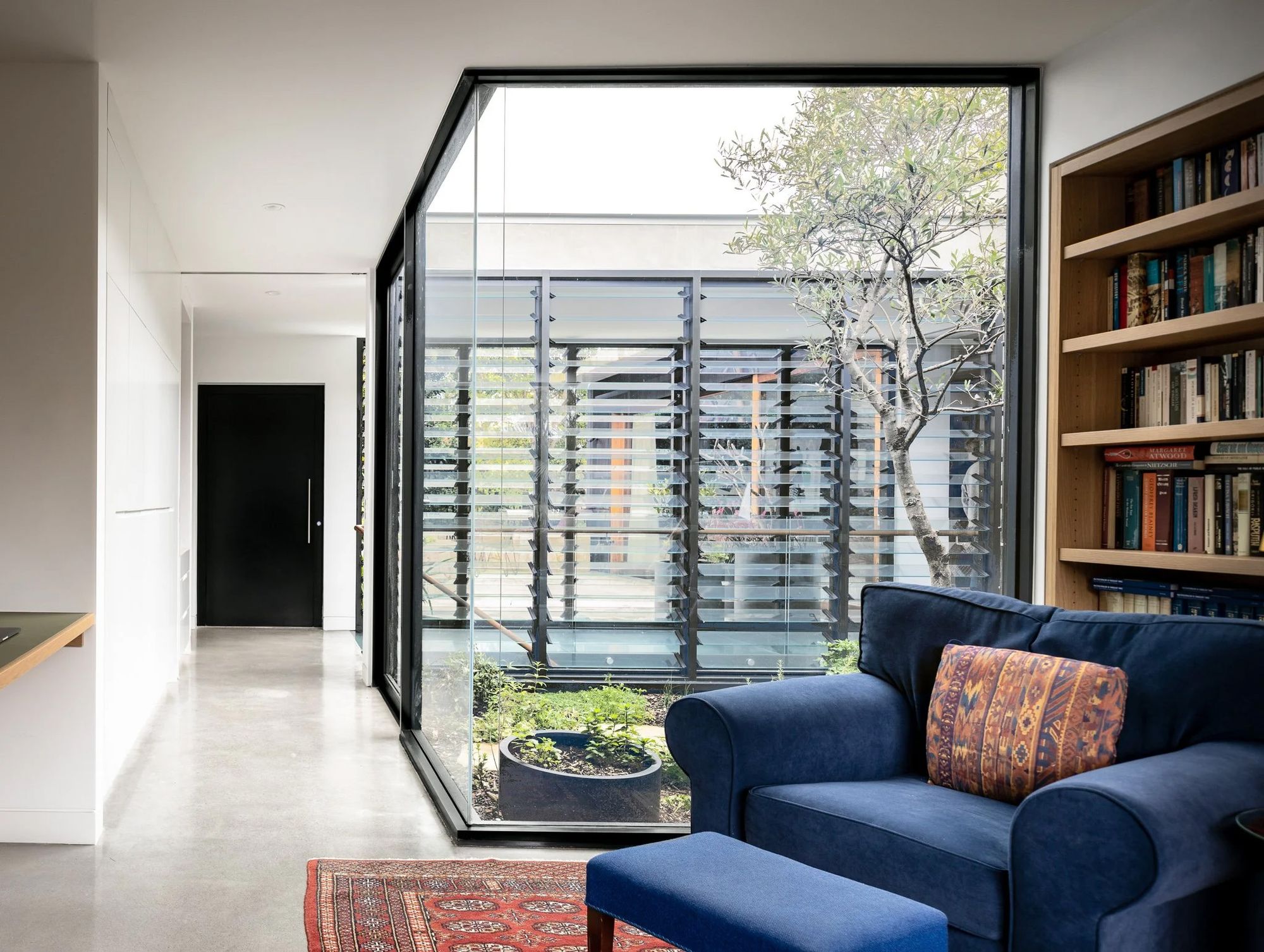 Blue sofa beside a library window looking into the courtyard