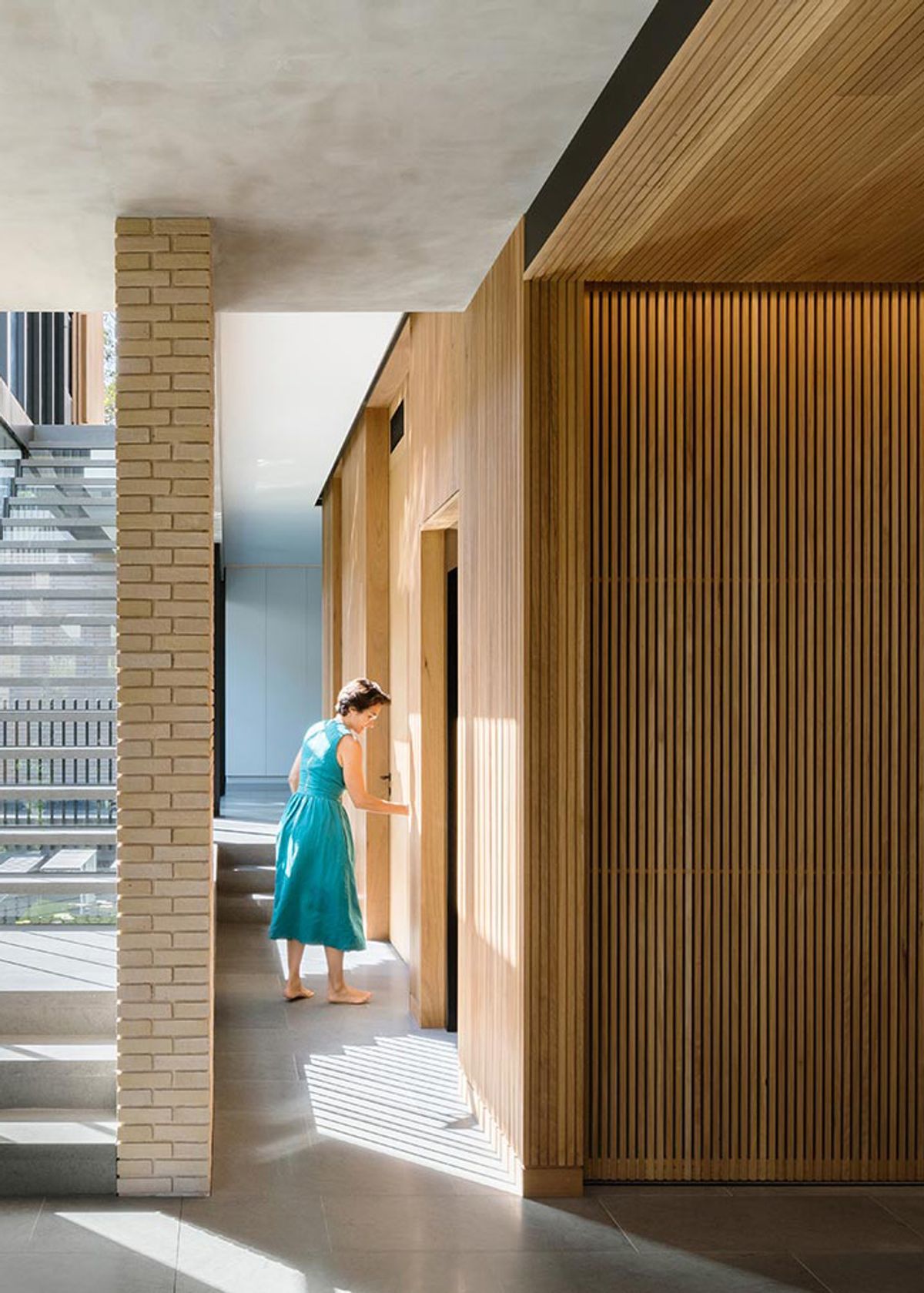 Timber lined hallway at Balmoral House with a brick column, a woman passing through a doorway