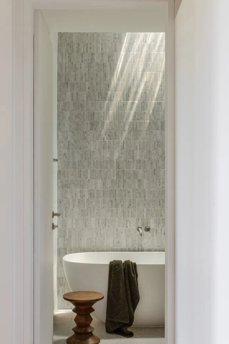 Bathroom with a freestanding bath, mosaic wall and a timber stool