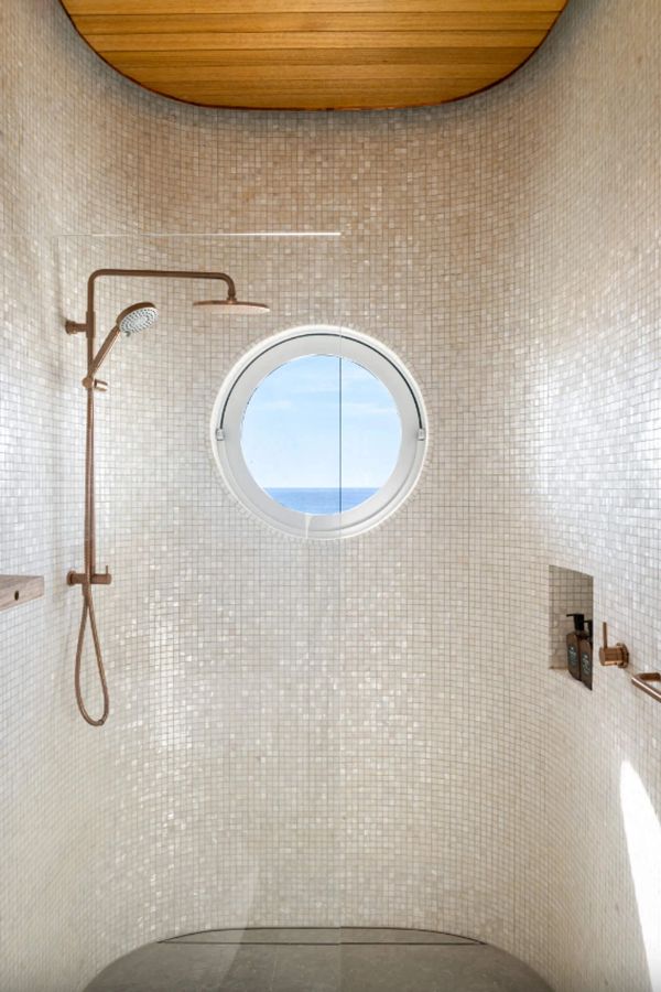 Mosaic tiled shower with a round porthole window at Swell and High Swell
