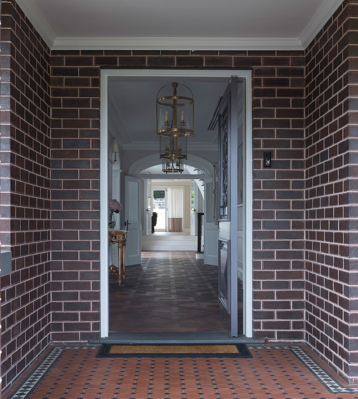 Brick entry porch at Sussex House with a tiled floor and a view through the front door