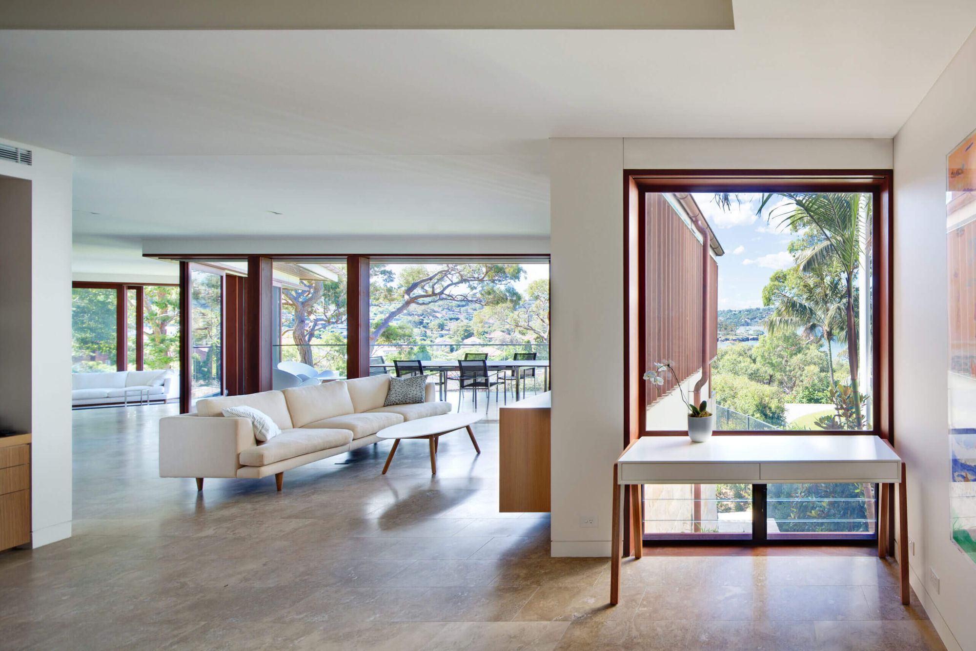Quiet House living room with a white sofa and a timber framed window seat looking to the trees