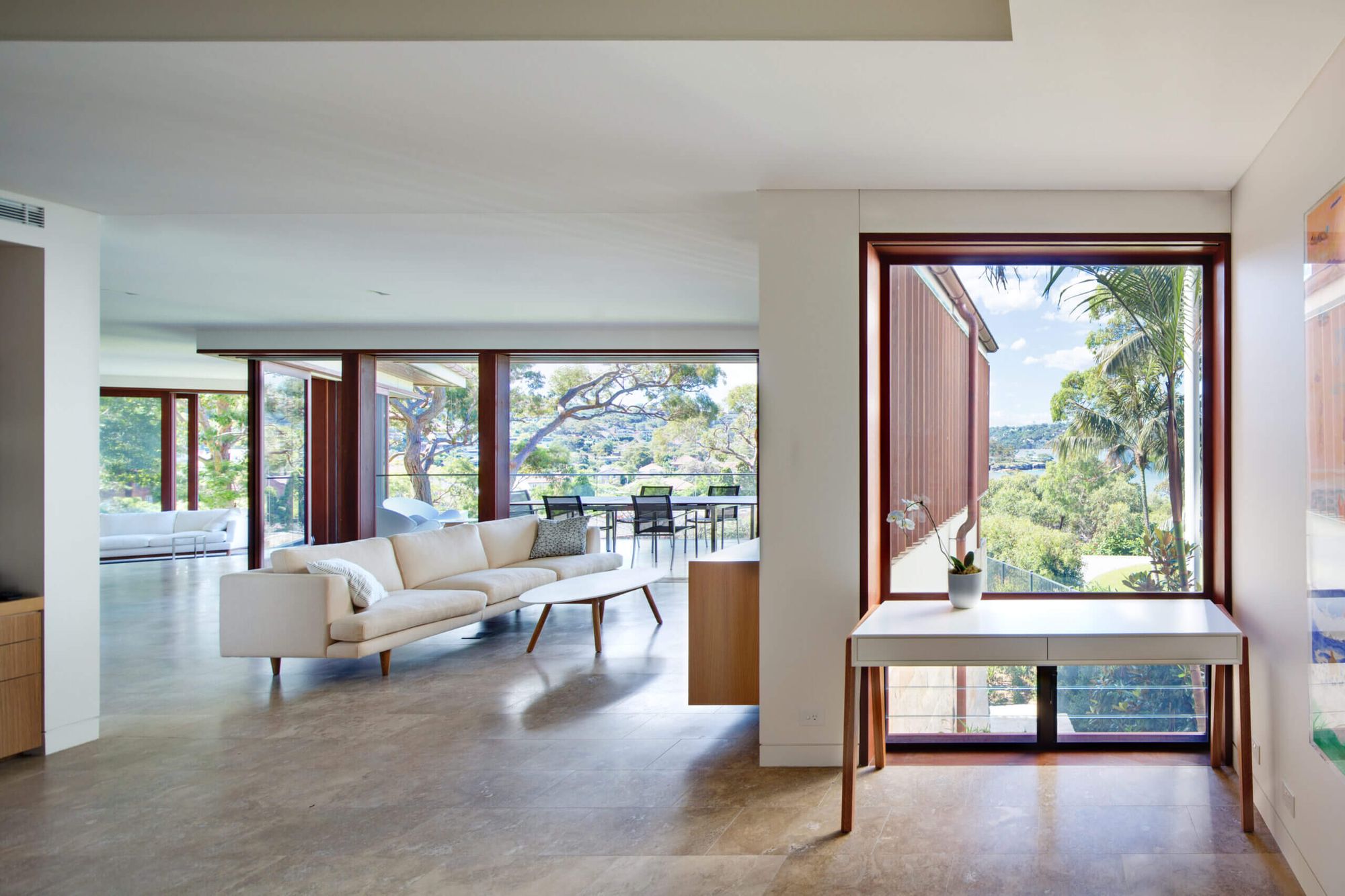 Quiet House living room with a white sofa and a timber framed window seat looking to the trees