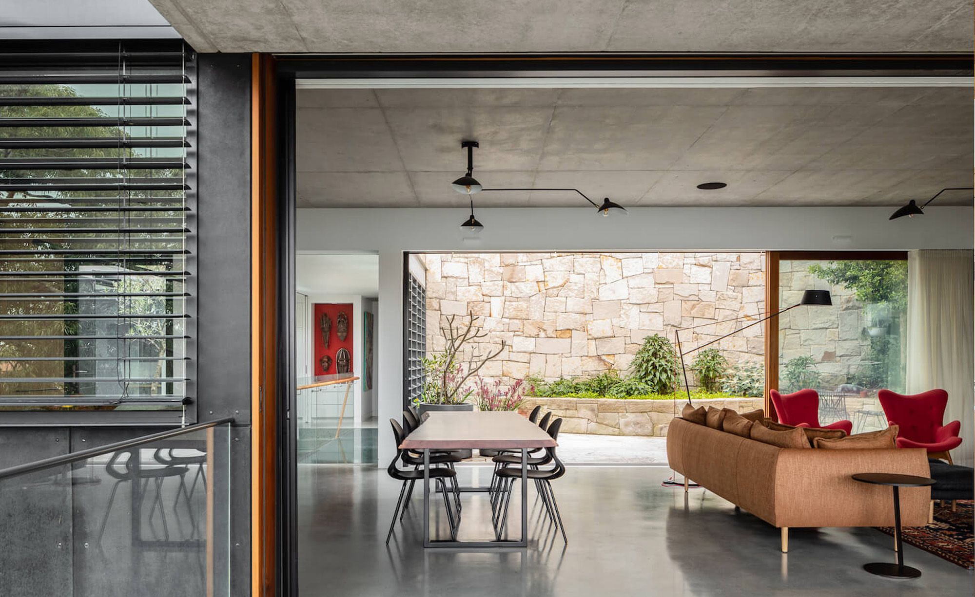 Living room opening through louvres to a sandstone courtyard