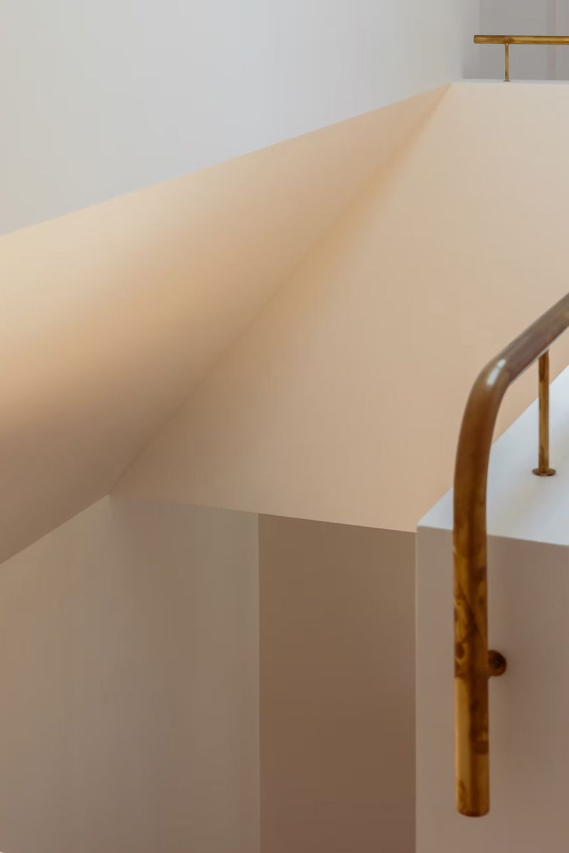 Brass handrail on a curved white stair wall
