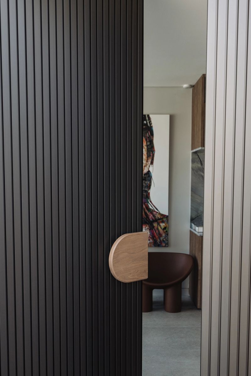 Dark battened door with a round timber handle opening to a hallway