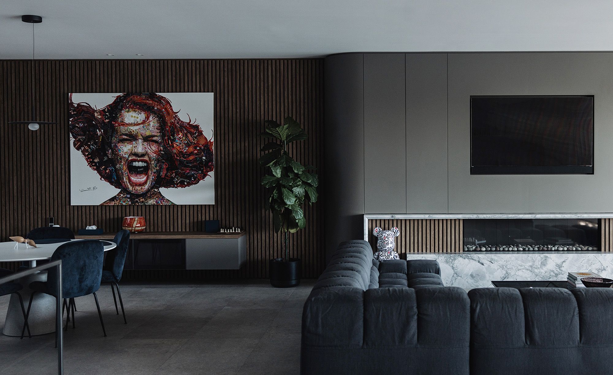 Living room with a large portrait artwork, timber battened wall and fireplace