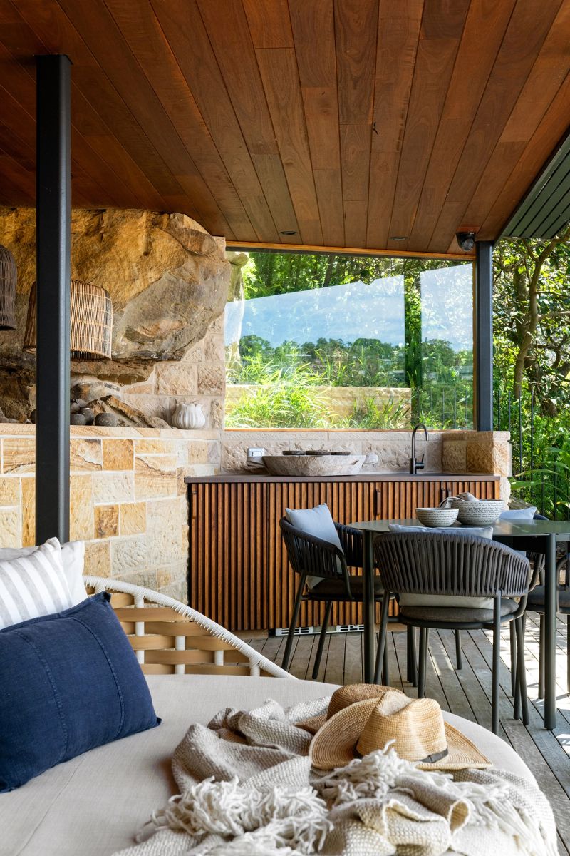 Covered terrace with a daybed and outdoor kitchen against the sandstone cliff