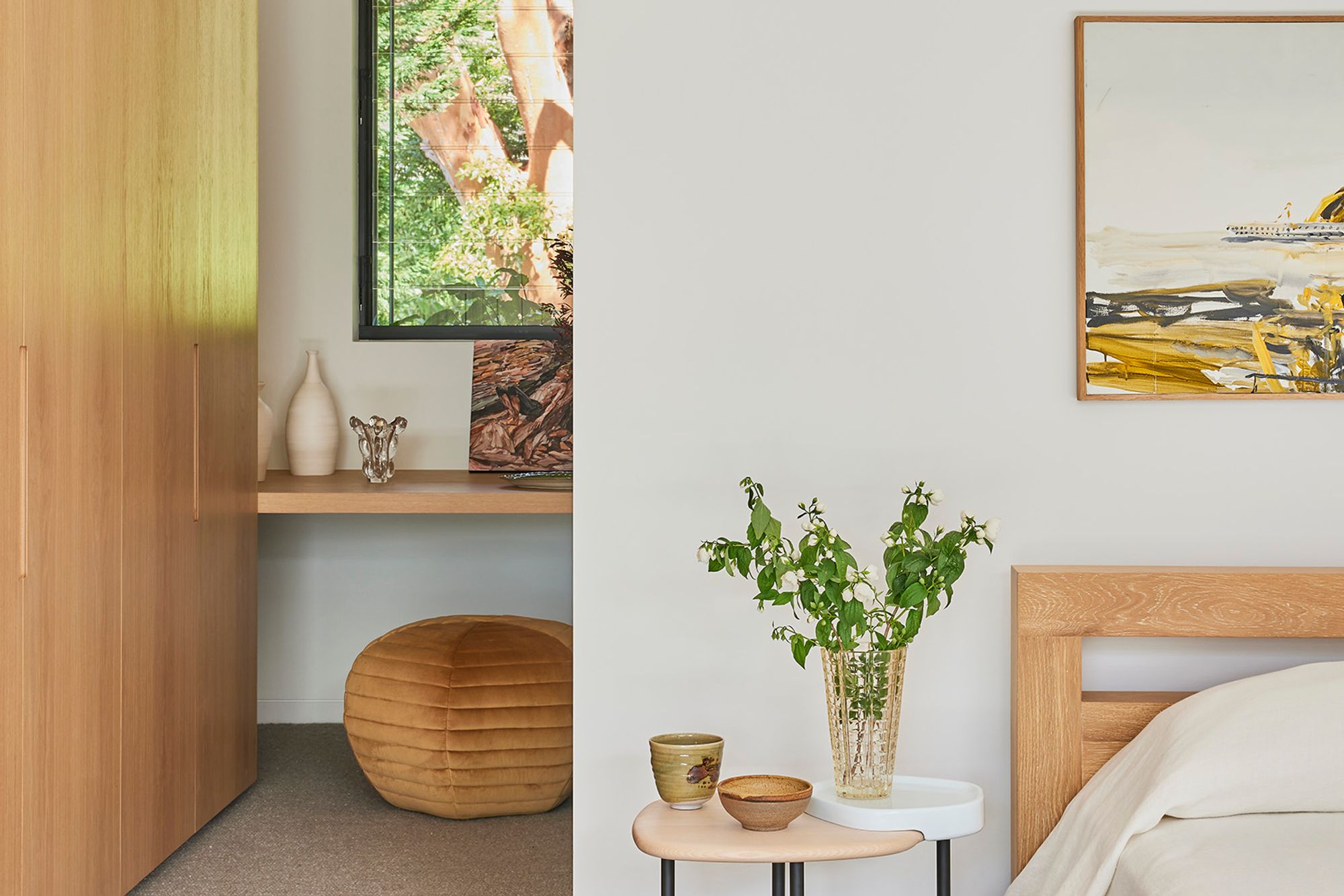 Bedroom corner with a timber bedhead, a small table and an artwork