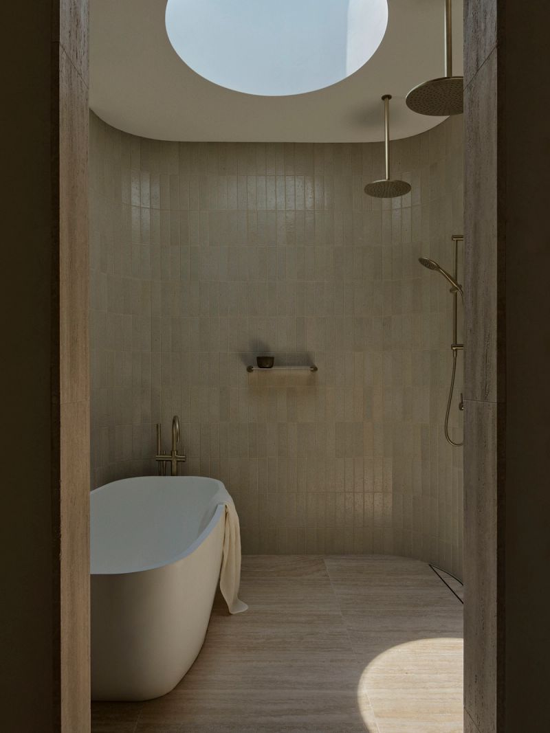 Bathroom with a freestanding bath under a round skylight and a walk in shower