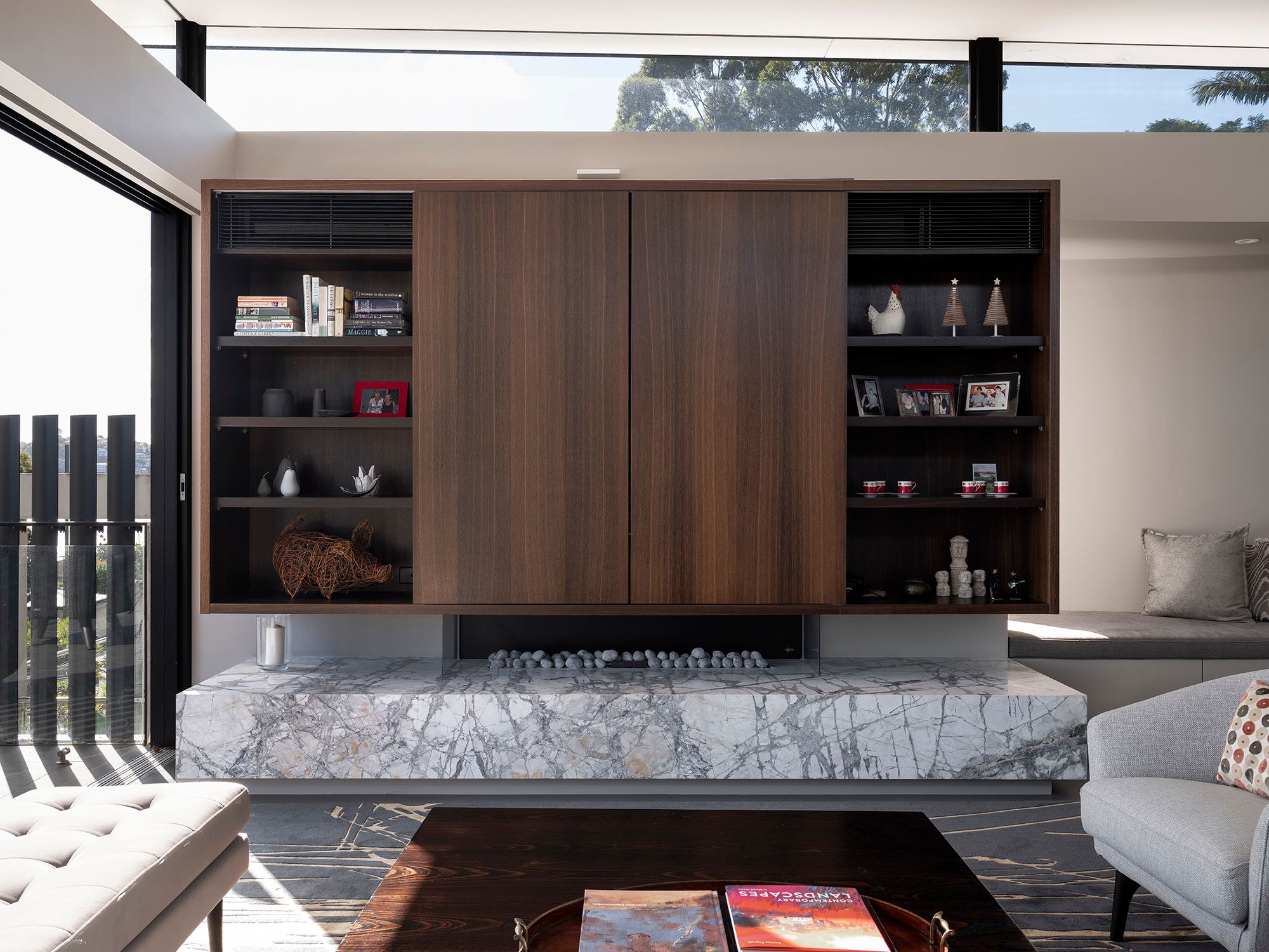 Living room with a timber joinery wall, marble fireplace bench and a view to the water