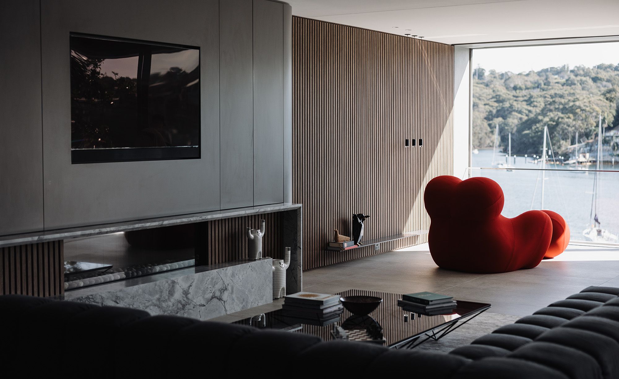 Living room with a red sculptural armchair and views to the harbour