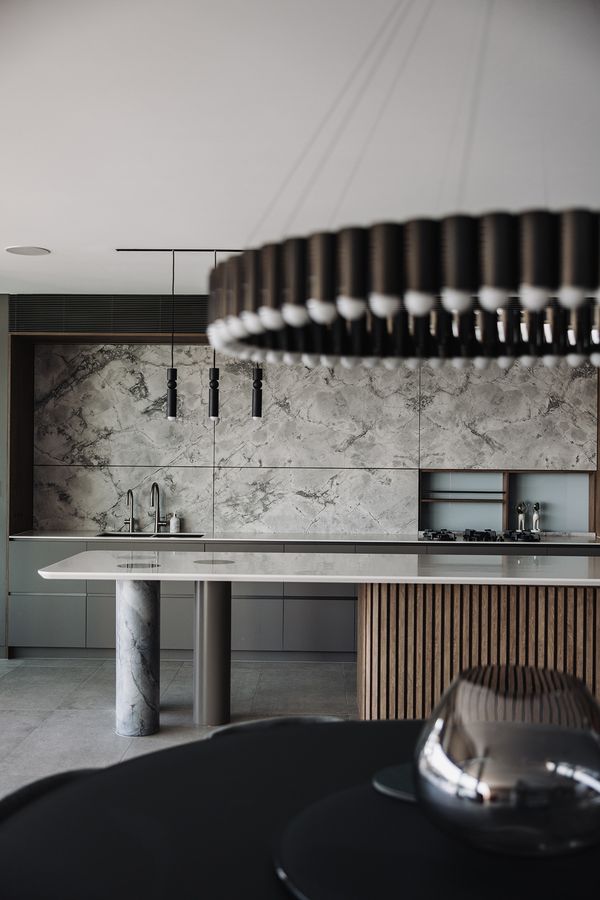 Shellbank kitchen with a marble splashback, stone island and a ring of pendant lights