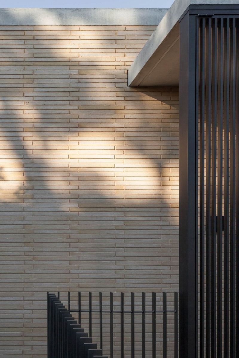Pale brick wall meeting a concrete soffit and steel battens at Balmoral House