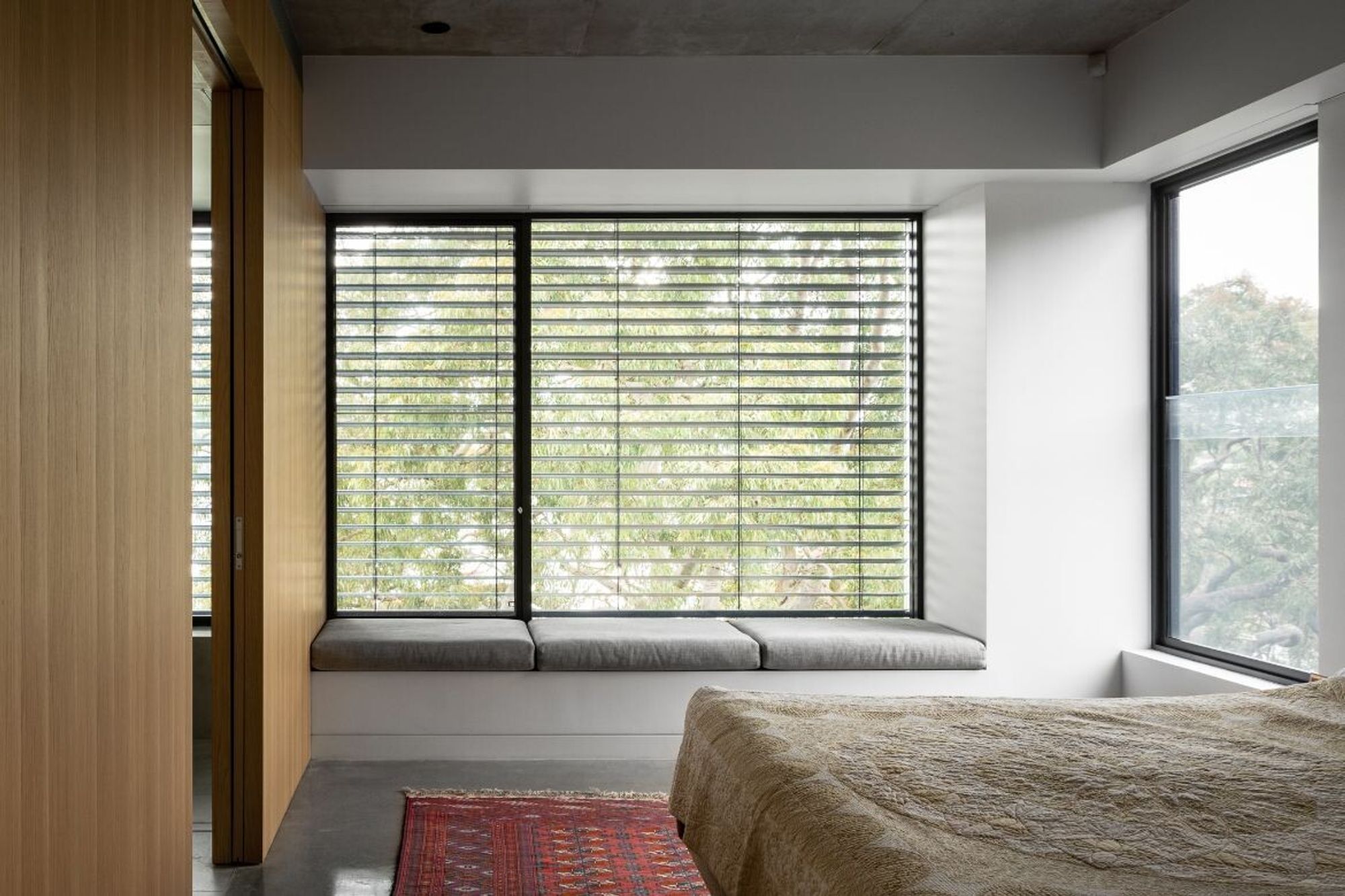 Bedroom with a window seat and louvre windows to the trees