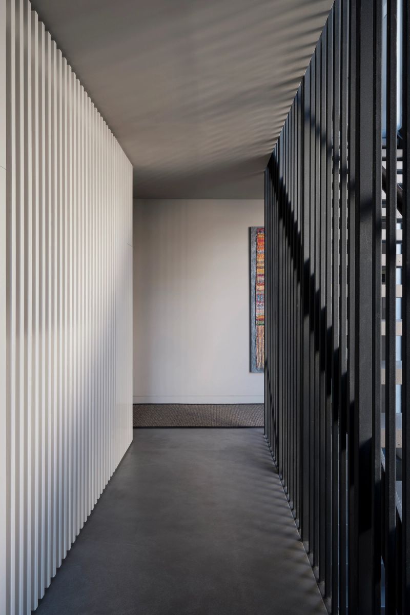 White ribbed wall and black steel battens in a hallway at Shellbank House