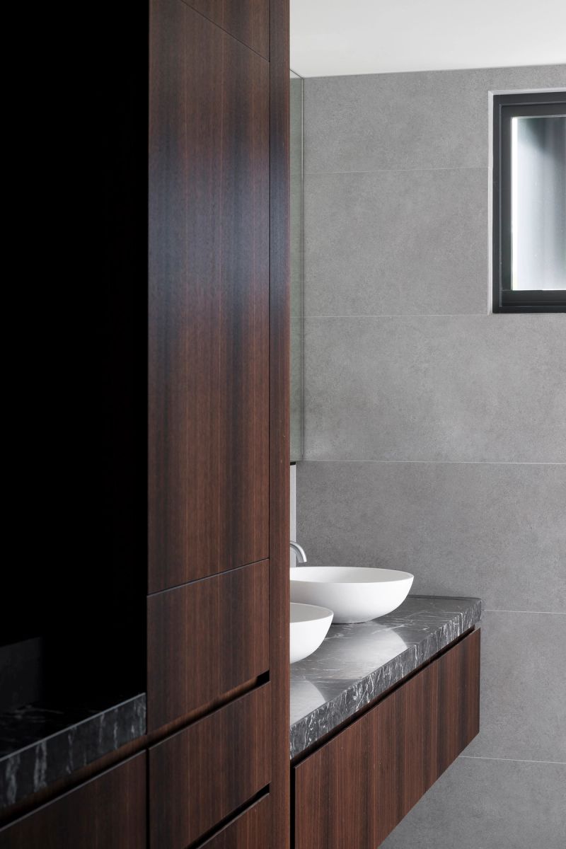 Bathroom with a round basin on a stone vanity and dark timber joinery