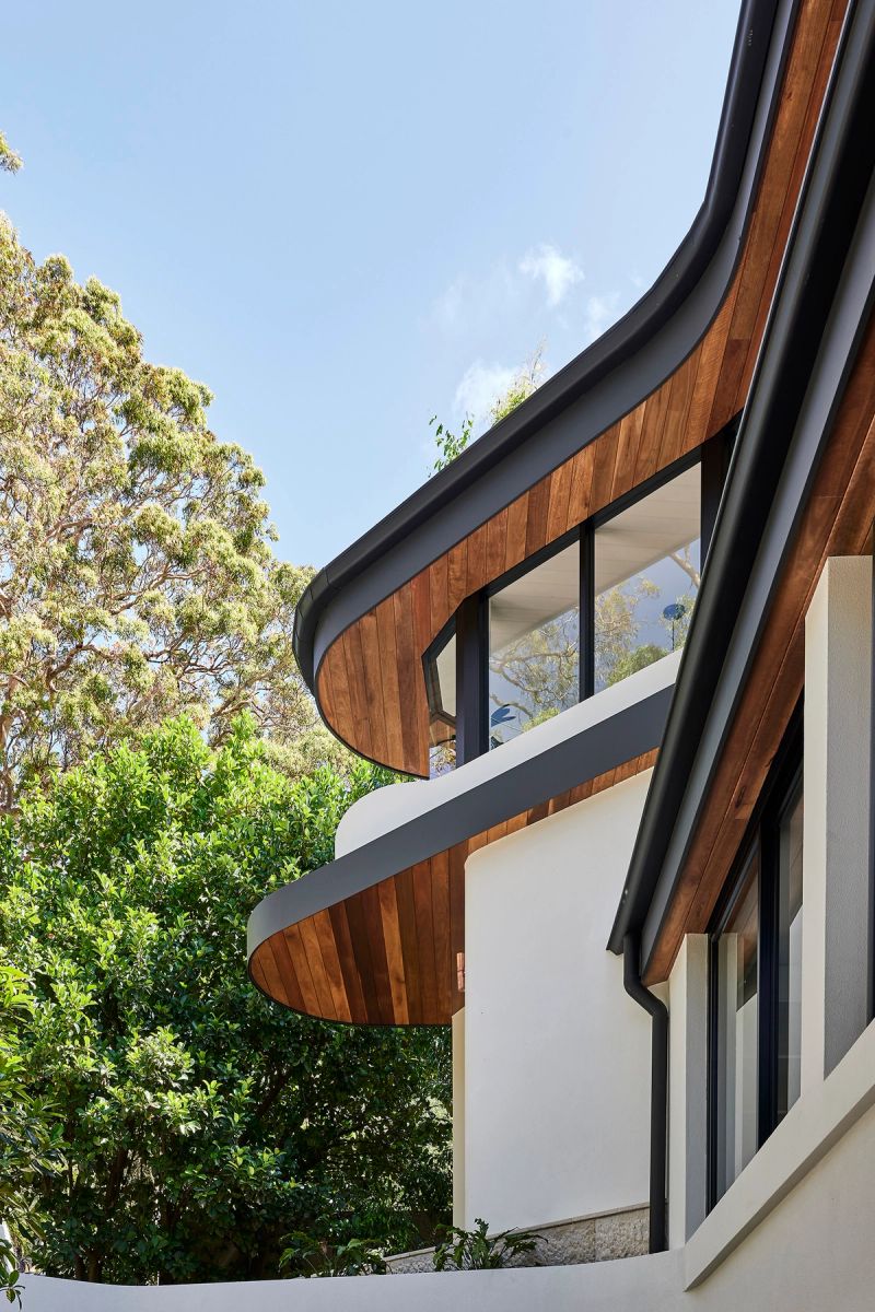 Curved timber clad balconies of Cobbittee House against the trees