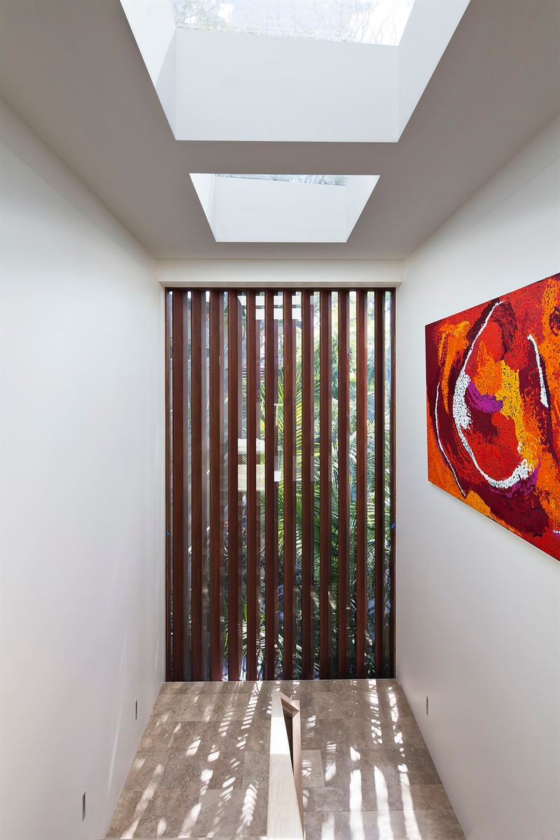 Hallway with two skylights, a timber batten screen and a red abstract artwork