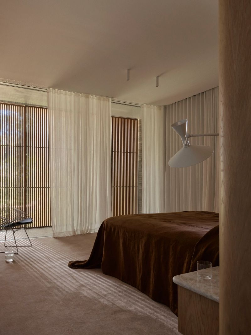 Bedroom with sheer curtains, timber screens and a wall mounted reading light