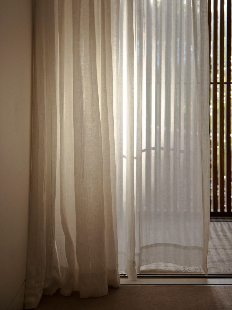 Sheer linen curtains beside a timber screen in afternoon sun