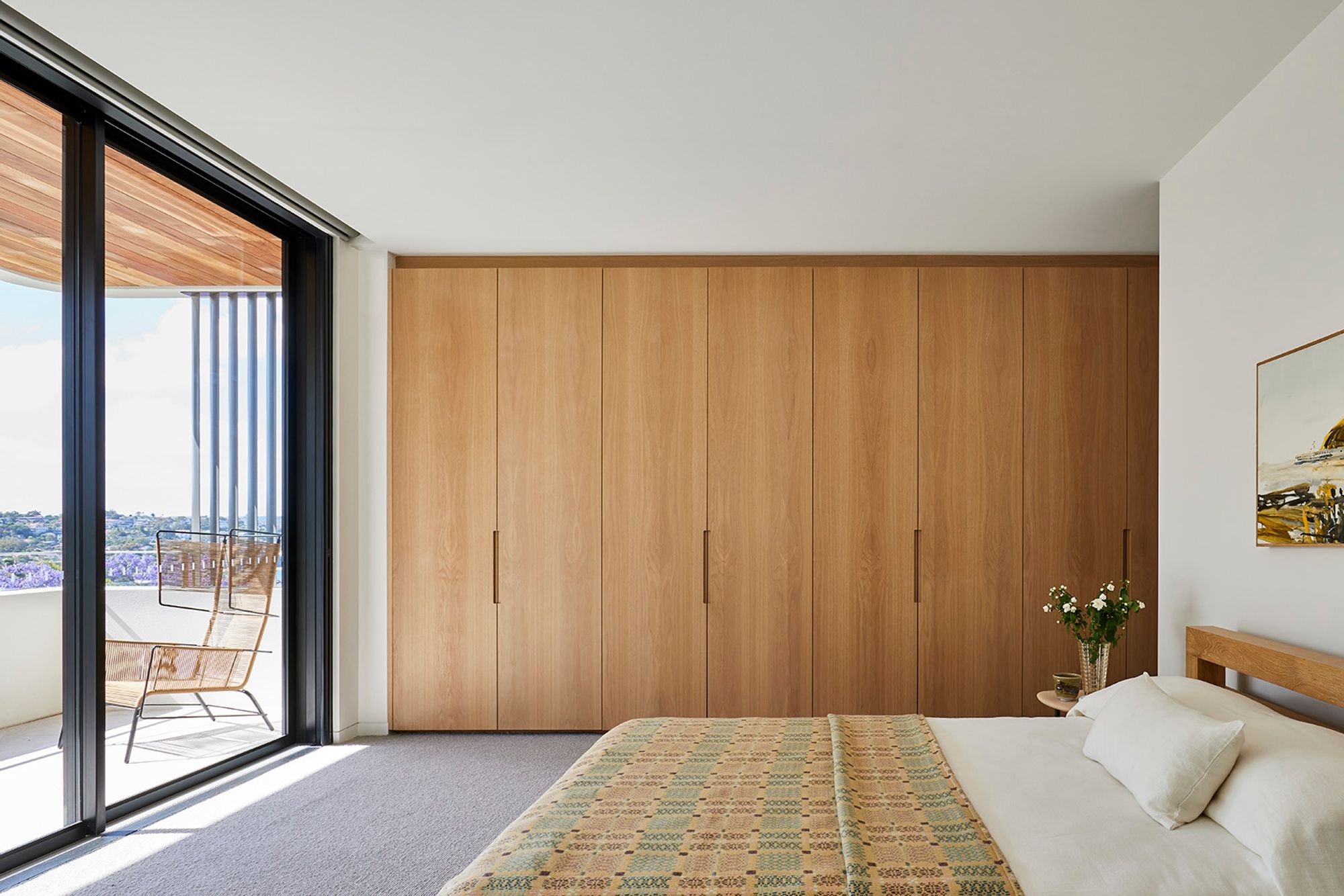 Bedroom with timber wardrobes opening onto a balcony