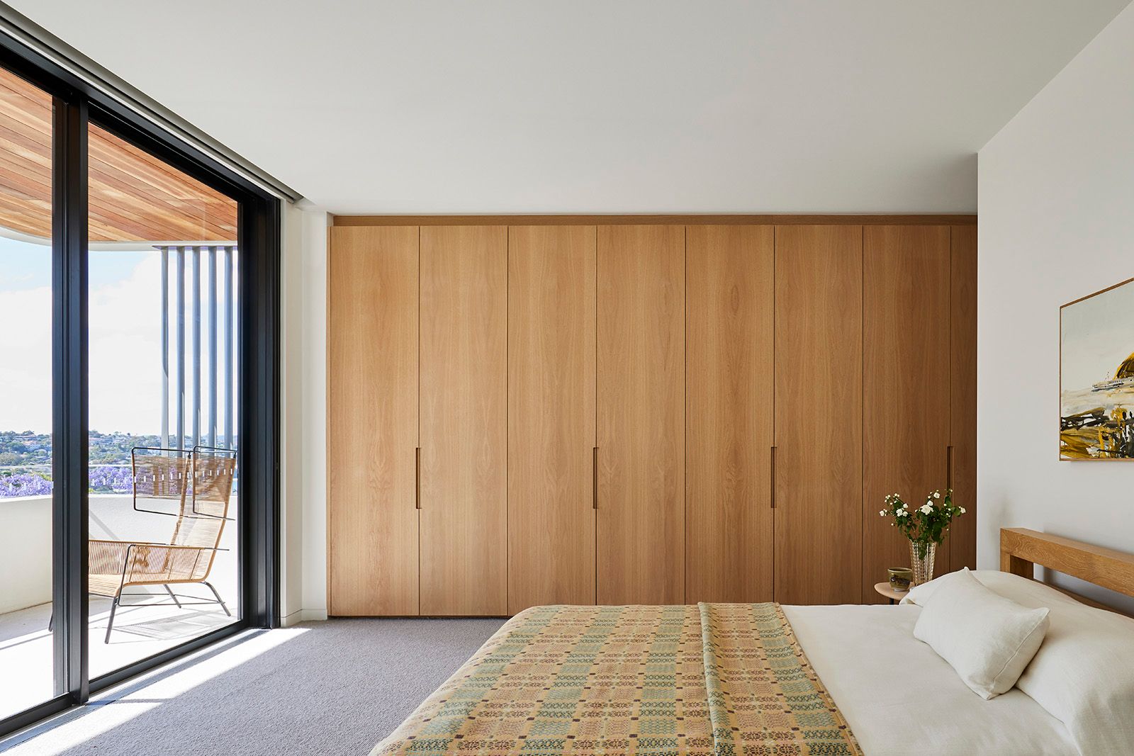 Bedroom with timber wardrobes opening onto a balcony