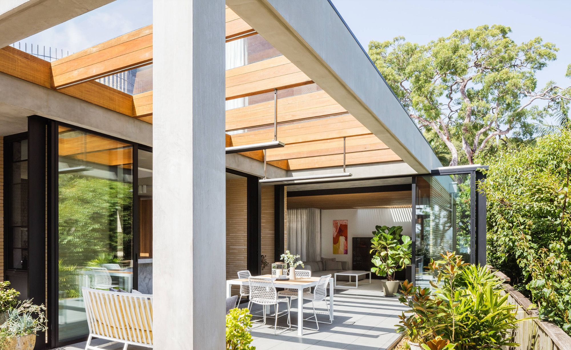 Covered terrace with a dining table and a timber batten roof beside the garden