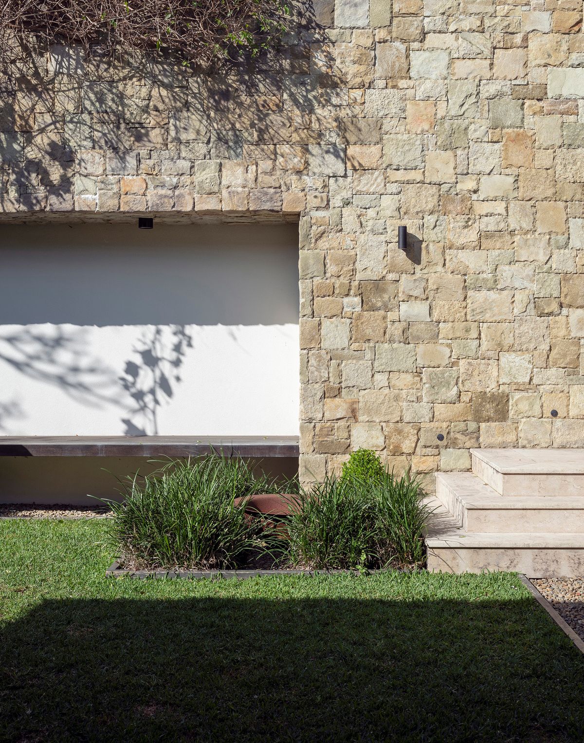 Sandstone wall and lawn at Shellbank House with a rendered fireplace niche