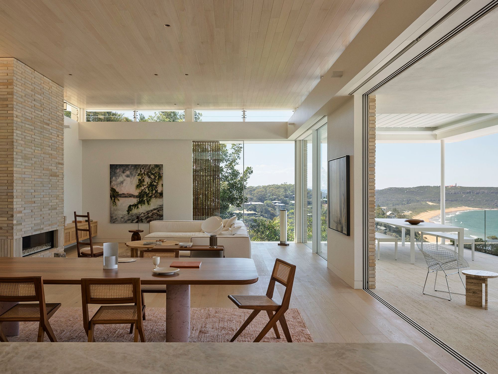 Open plan dining and living room at Breeze House with glass walls to the terrace and the coast