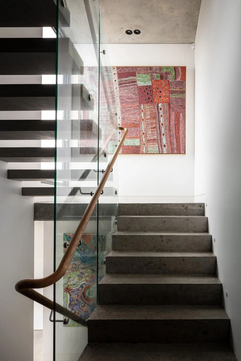 Concrete stair with a glass balustrade and a red artwork at the landing